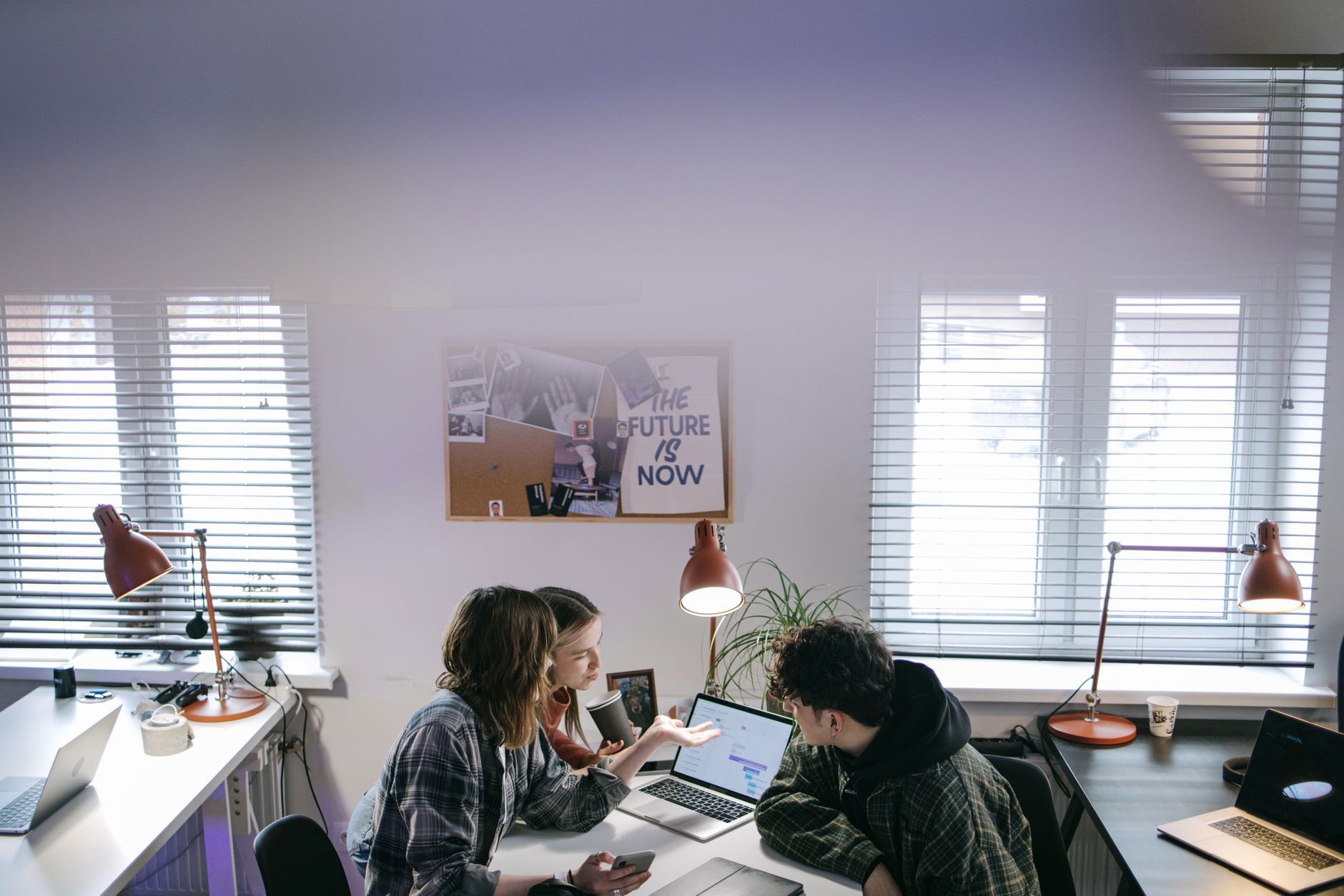A group of people discussing ideas around laptops in a bright, modern office space — illustrating: Cybersecurity Solutions for SMBs in Central Florida: Managed vs In-House Defense in 2026