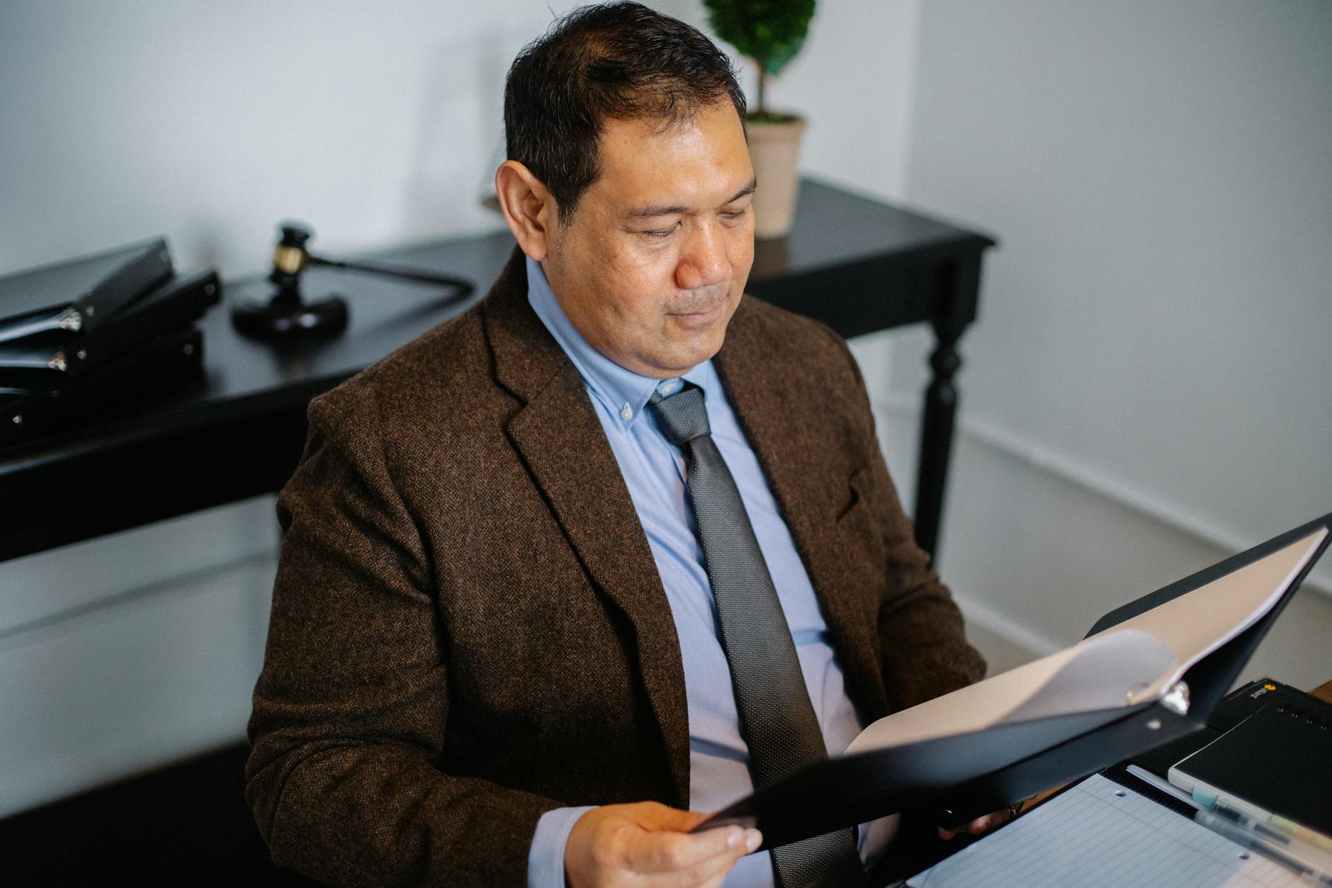 From above of serious ethnic lawyer in elegant suit checking report in folder on blurred background of office — illustrating: How To Choose Compliance Software for Central Florida Businesses Without Breaking Your IT Budget