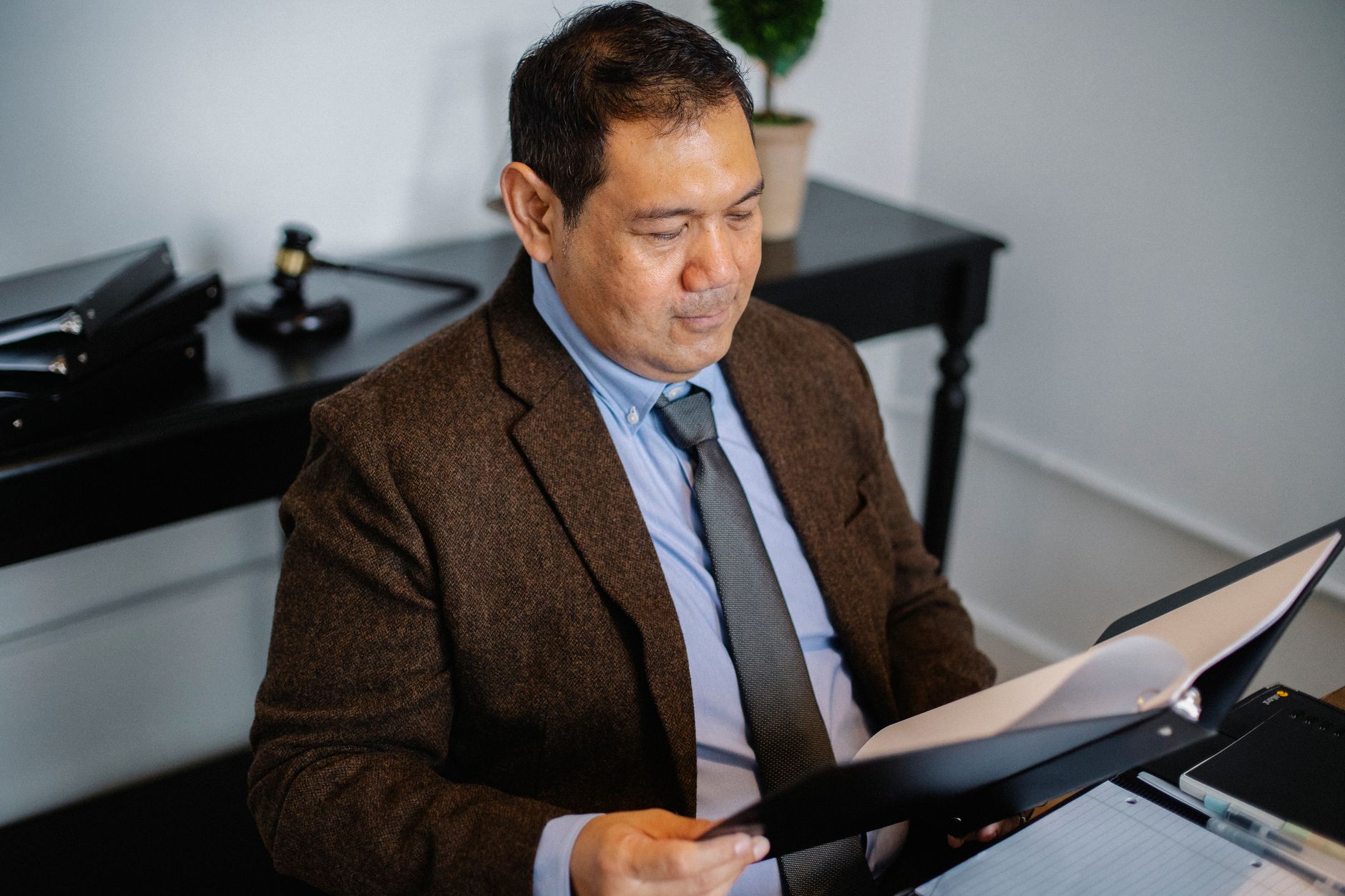 From above of serious ethnic lawyer in elegant suit checking report in folder on blurred background of office — illustrating: HIPAA Compliance Checklist for Central Florida Medical Practices: A Mid-Year Guide (2024)
