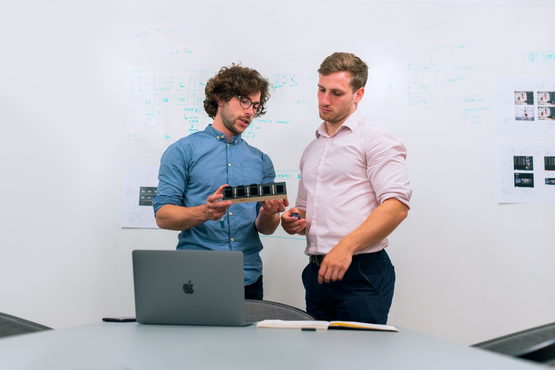 Two men in an office discussing and reviewing a tech prototype — illustrating: Small Business Cloud Backup Comparison in Central Florida: Speed, Cost, and Recovery Time Evaluated